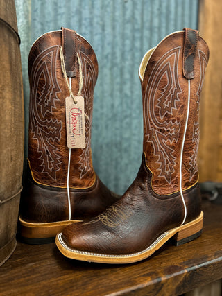 Pair of brown cowboy boots with intricate designs on a wooden surface.