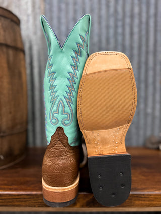 Turquoise cowboy boot with brown sole on a wooden surface