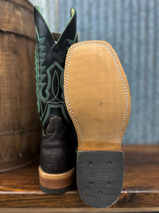 Close-up of a cowboy boot with a focus on the sole and heel, against a rustic background.