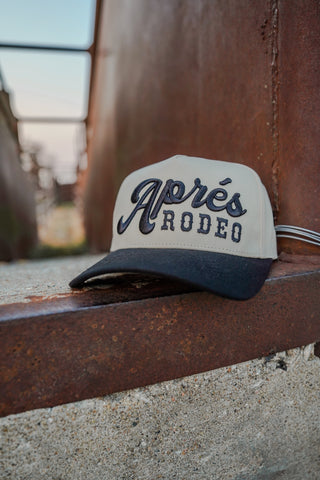 Cap with 'Aprés Rodeo' text on a wooden surface