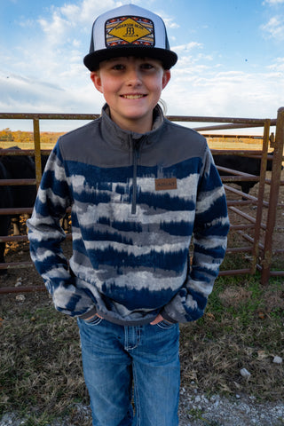 Child wearing a blue and gray striped sweater and cap outdoors with a fence and sky in the background