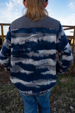 Person wearing a blue and gray striped shirt with a blurred background