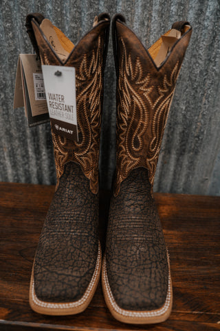 Pair of brown cowboy boots with intricate designs on a wooden surface.