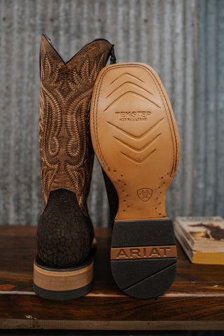 Brown cowboy boot with intricate design on a wooden surface and metal background