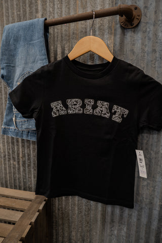 Black t-shirt with white text on a wooden hanger against a textured wall.