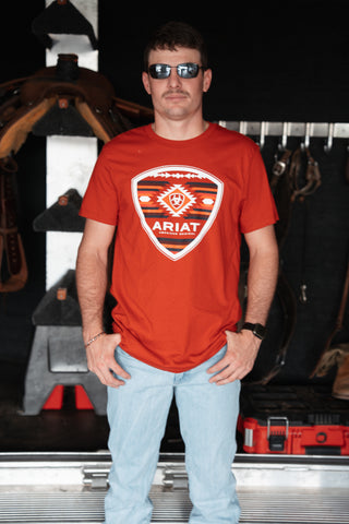Man wearing a red Ariat t-shirt standing in front of a store display.