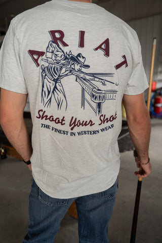 Person wearing a gray t-shirt with ARIAT branding and graphic design.