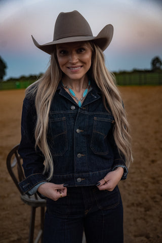 Woman wearing a cowboy hat and denim jacket in an outdoor setting