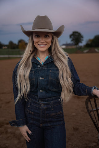 Woman wearing a denim outfit and cowboy hat in an outdoor setting