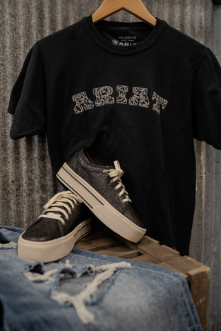 Black t-shirt with 'ABIE' logo, gray sneakers, and blue jeans on a wooden pallet against a corrugated metal background.