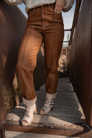 Person wearing brown pants and white shoes standing on a rustic wooden staircase.