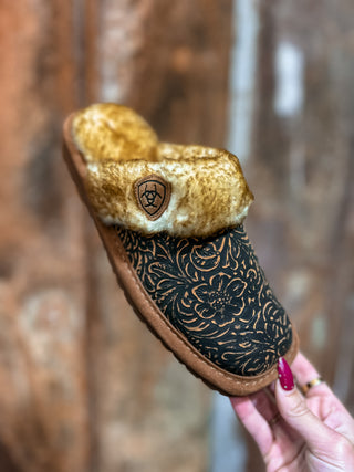 Brown slipper with gold interior held by a hand against a blurred background