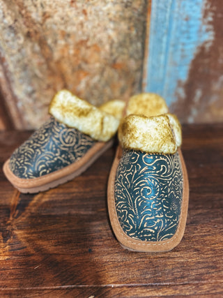 Pair of decorative slippers with gold bows on a wooden surface