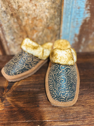Pair of decorative shoes with gold bows on a wooden surface