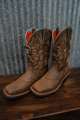 Pair of brown cowboy boots with intricate designs on a wooden surface and textured gray background