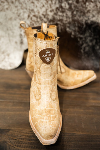 Beige Ariat boots on a wooden surface with a textured background