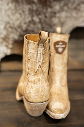 Pair of beige boots with a brand logo on a wooden surface