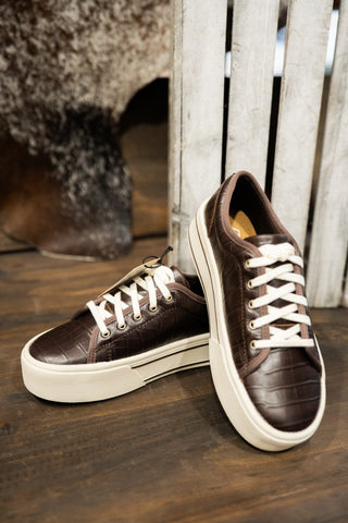 Brown sneakers with white laces on a wooden floor