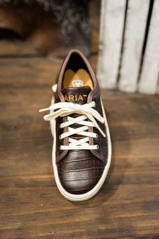 Brown leather shoe with white laces on a wooden floor