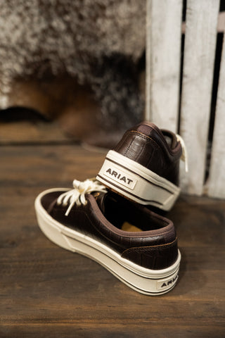 Brown Ariat shoes on a wooden surface with a blurred background