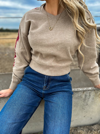 Person wearing a beige sweater and blue jeans with a blurred background