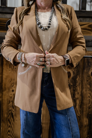 Person wearing a brown coat with a wooden background