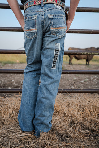 Person wearing blue jeans with a cow in the background