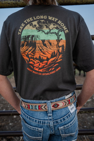 Person wearing a black t-shirt with a scenic design and text, standing on train tracks.