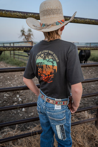 Person wearing a cowboy hat and t-shirt with a graphic design, standing in front of a metal fence.