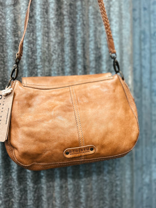 Brown leather handbag with a visible brand tag on a textured blue background