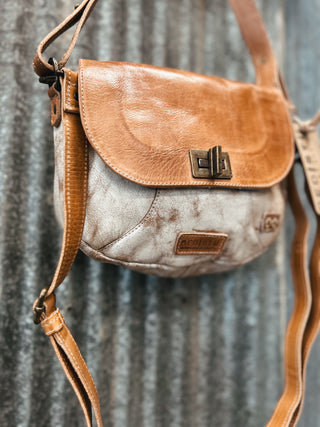Brown leather crossbody bag with a visible brand logo on a textured metal background