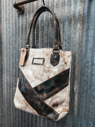 Vintage-style handbag with a distressed leather design against a corrugated metal background
