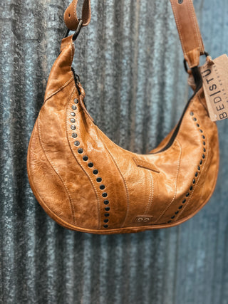 Brown leather handbag with studded details on a textured gray background