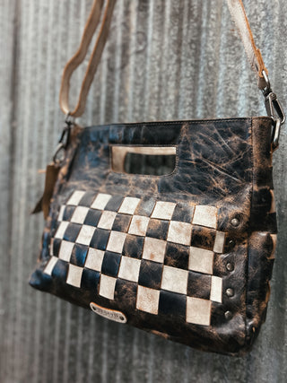 Handbag with checkered pattern and leather strap on a textured background