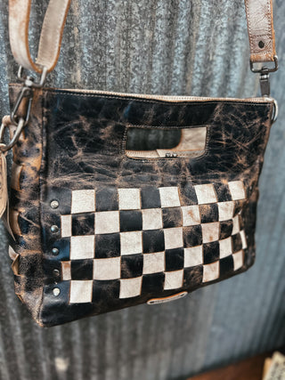 Brown leather handbag with checkered pattern on a textured surface