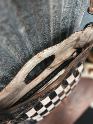 Close-up of a leather bag with checkered pattern on a wooden surface
