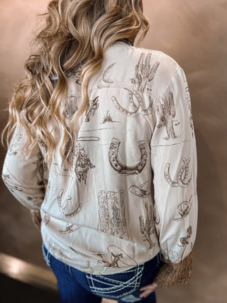Person wearing a white blouse with cowboy-themed patterns against a neutral background