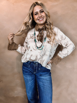 Woman wearing a patterned blouse and blue jeans against a beige background
