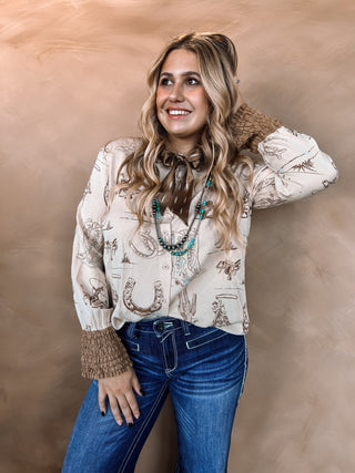 Woman wearing a patterned blouse and jeans against a beige background