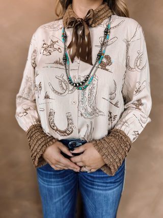 Person wearing a patterned shirt with horse and cowboy boot designs, brown gloves, and a scarf.