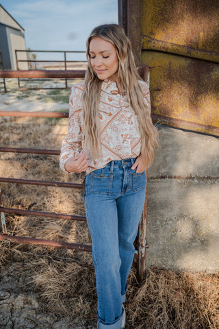Woman standing by a rustic metal gate with hay on the ground