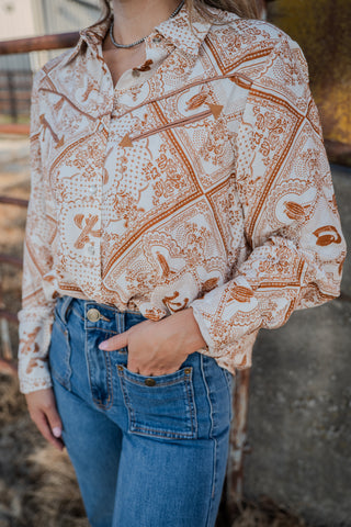Person wearing a patterned blouse and blue jeans with a blurred background