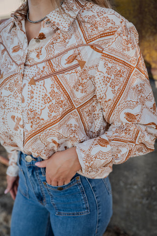 Person wearing a patterned shirt and blue jeans with a blurred background