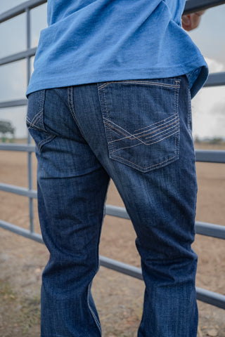Person wearing blue jeans and a blue shirt standing near a metal gate.