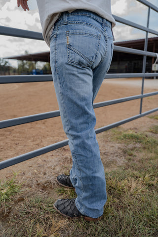 Person wearing blue jeans standing near a metal gate in an outdoor setting