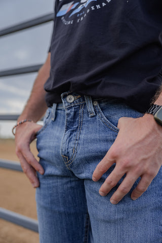 Person wearing a dark blue t-shirt and light blue jeans with a blurred background