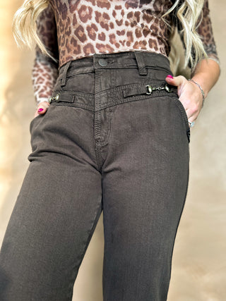 Person wearing a leopard print top and dark gray pants against a neutral background