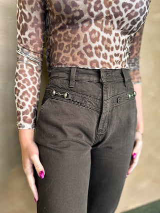 Person wearing a leopard print top and dark pants against a neutral background