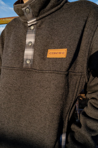Close-up of a brown jacket with a Cinch logo on a blurred background