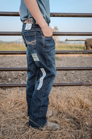 Person wearing blue jeans standing near a metal fence with a blurred background